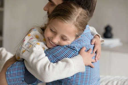 Smiling cute little child girl cuddling loving young father at home, missing after long separation...