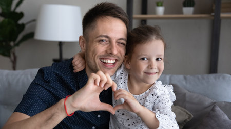 Happy cheerful dad and adorable daughter girl making finger heart at camera, showing symbol of love, tenderness, gratitude, affection. Father and kid bonding, family. Head shot portrait, bannerの写真素材