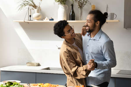 Distracted from cooking happy active young loving African American married couple dancing to disco...