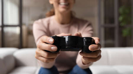 Close up cropped of excited woman using remote controller, playing video game on console or computer...