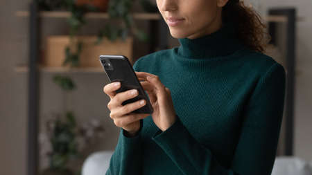 Close up of young Latino woman use modern cellphone gadget browse wireless internet or shopping...