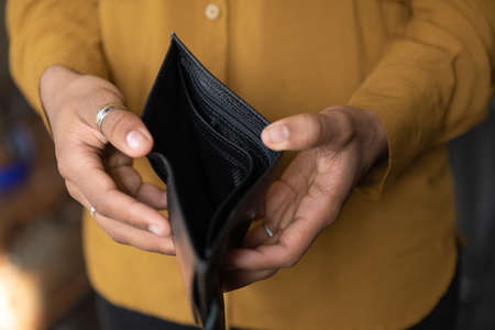 Close up young African American unemployed woman holding opened empty black leather wallet. feeling stressed without cash, having financial problems, suffering from lack of money, bankruptcy concept.の写真素材