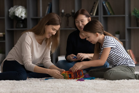 Leisure time. Happy tween girl young mother old age grandmother spend free time on carpet create...