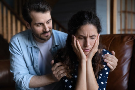 Unhappy young man apologizing to stressed stubborn beautiful woman, feeling guilty for offend or misunderstanding. Emotional worried frustrated millennial family couple having problems in relations.の写真素材