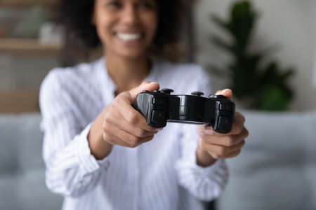 Close up focus on remote controller in female hands, joyful laughing african ethnicity biracial...