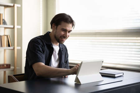 Happy young businessman entrepreneur freelancer using digital touchpad gadget, enjoying working...