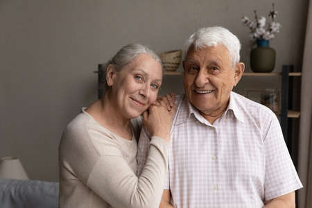 Portrait of smiling sincere affectionate older 60s beautiful hoary woman putting head on shoulder of...