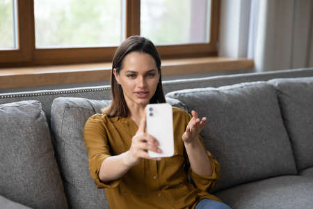 Beautiful millennial telephone caller woman talking on mobile phone, making conference call from...