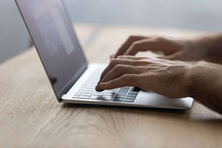 Crop close up male hands typing on modern laptop keyboard, businessman freelancer or student working...
