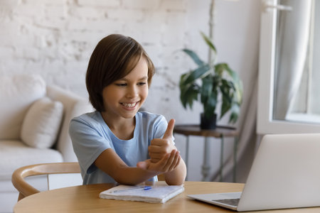 Smiling positive teen pupil boy with hearing disability studying online from home, talking on video...