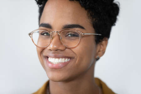 Face of happy beautiful short haired African American girl in stylish glasses smiling at camera with...
