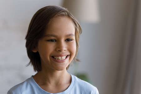 Happy lovely pre teen boy candid portrait. Cheerful young kid guy looking away with toothy smile,...