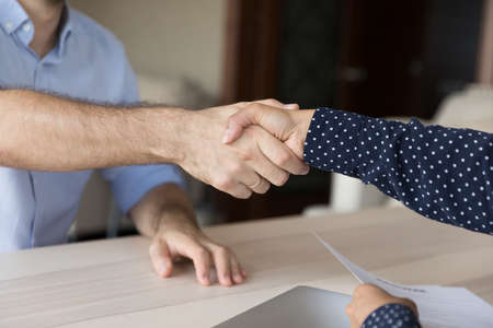 Close up confident Caucasian man shaking hands with Indian female partner, making agreement after...
