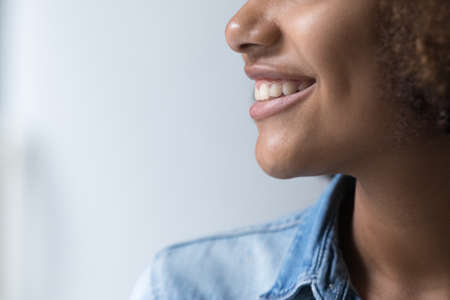 Lower face of happy beautiful Black ten girl side view. Close up cropped shot of pretty young woman,...