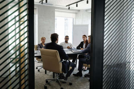 Candid shot of diverse team working together, discussing project at table in meeting room. Business...