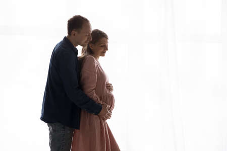 Peaceful happy expecting couple enjoying closeness, awaited parenthood, standing against day natural...