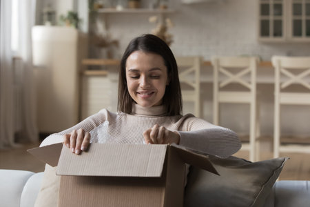 Satisfied client of e-commerce get long-awaited parcel ordered on internet, woman opens box smiles...