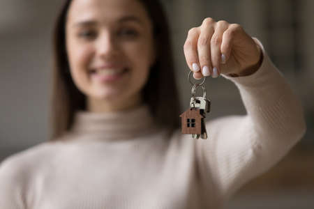 New house owner at relocation day, real-estate agent offering profitable dwelling to client, bank loan, mortgage concept. Happy young female showing to camera bunch of keys from first home, close upの写真素材
