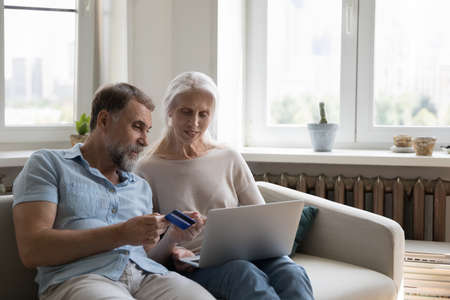 Mature spouses buy electronic services, order goods for home, e-commerce retail e-services happy...