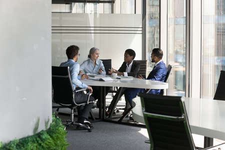 Multiethnic business team discussing project in meeting room. Female corporate leader instructing...