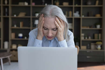 Tired frustrated senior business woman suffering from headache, migraine, high blood pressure,...
