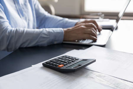 Female business professional workplace with calculator, financial documents, paper bills for...