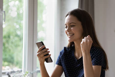 Joyful happy cellphone user girl feeling joy, getting good news, using online shopping app on mobile...