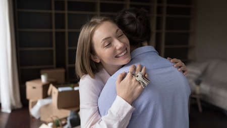 Loving wife and husband hugging in unfurnished living room with belongings packed in cardboard boxes, start new life, congratulate each other with relocation to own first house. Tenant, love conceptの写真素材
