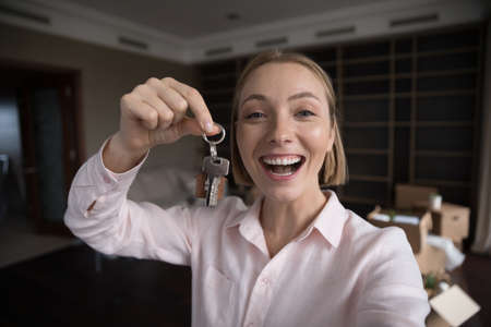 Head shot portrait happy millennial blonde female new renter of dwelling, showing bunch of keys on camera, web cam view. Proud excited homeowner portrait, new dwelling, tenancy, bank mortgage conceptの写真素材