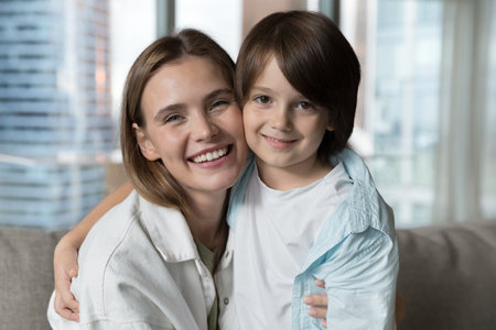 Happy pretty young mom hugging adorable little son cheek touches, feeling love, affection, smiling, laughing, looking at camera with toothy smile, enjoying happiness, family leisure, motherhoodの写真素材