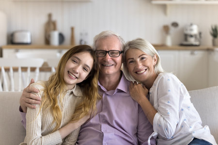 Cheerful older grandfather enjoying leisure with wife and grandkid, looking at camera, smiling,...