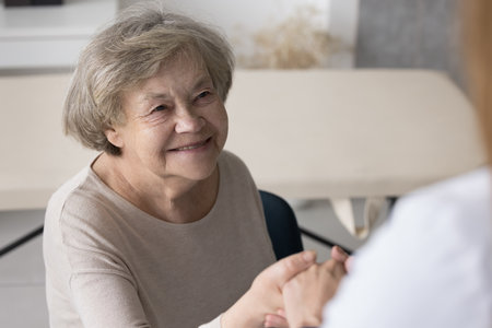 Positive optimistic older 80s lady visiting practitioner, consulting doctor in office, listening to...