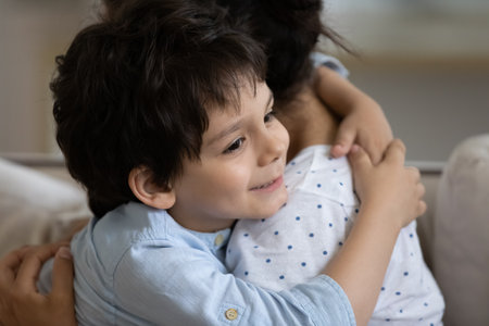 Close up 5s boy hugging Indian mother, family enjoying tender moment, smiling adorable son child and caring young mom embracing, good relationship and trust, sitting on couch, motherhood conceptの写真素材