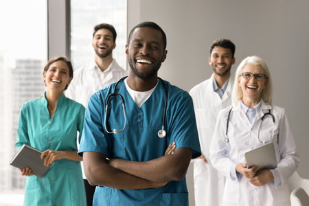 Happy African American surgeon man with folded arms standing in front of diverse colleagues, looking at camera, smiling, laughing. Small clinic head doctor, medical business leader portraitの写真素材