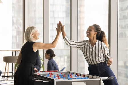 Cheerful diverse office friends women enjoying recreation activity on work break, playing tabletop...