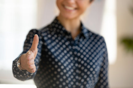 Happy young business woman in casual reaching hand at camera for shaking, giving palm for handshake, offering partnership, cooperation, agreement. Close up shot of female armの写真素材