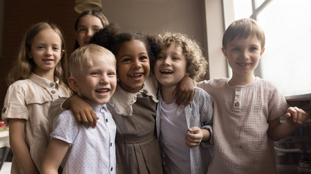 Cute six happy kids pose in art-studio, hugging enjoy creative hobby and friendship after painting classes. Portrait of cheerful multiethnic alpha generation girls and boys laughing looking at cameraの写真素材