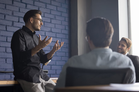 Successful attractive young boss leader gives presentation for clients in modern boardroom. Confident businessman leads corporate meeting, training staff, give instructions. Briefing, team-buildingの写真素材