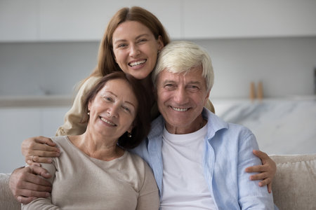 Cheerful mature mom, dad and adult young daughter woman having fun at home together, making hand...