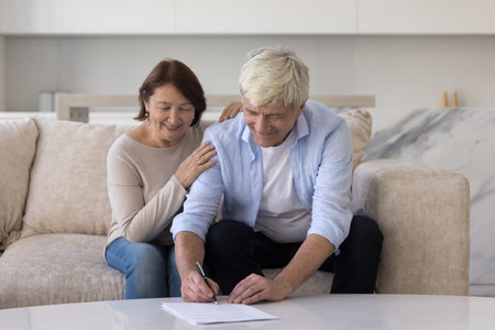 Happy senior customer signing retirement insurance agreement, investment, medical service contract, buying real estate property, writing. Positive agent woman meeting with couple of clientsの写真素材