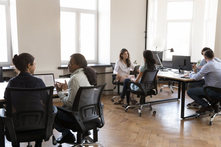 Pairs of diverse business colleagues working in modern office space, sitting at workplace desks, discussing project tasks, brainstorming, networking, cooperating on tasks, meeting for teamworkの写真素材