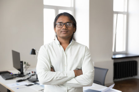 Serious successful Indian businessman in glasses office portrait. Confident middle aged startup...