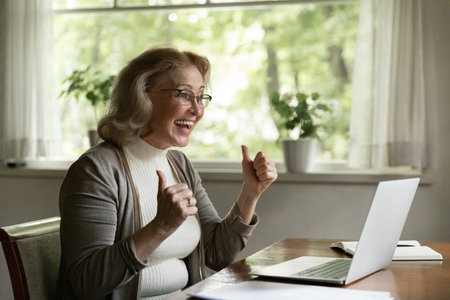 Excited with success. Overjoyed senior woman office worker look at laptop screen share good news by...