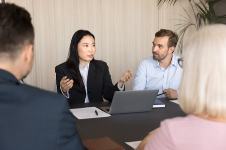 Serious young Asian business professional woman making report, offering ideas, solution for project,...