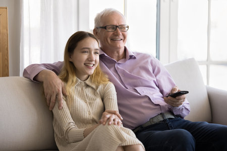 Pre-teen 14s girl spend time together with older 70s grandpa, switch channels, enjoy movie using...