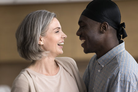 Close up profile view middle-aged multiethnic couple in love look each other with affection, spend...