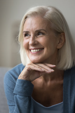 Close up vertical profile picture of satisfied pretty mature woman smiling, revealing perfect white...