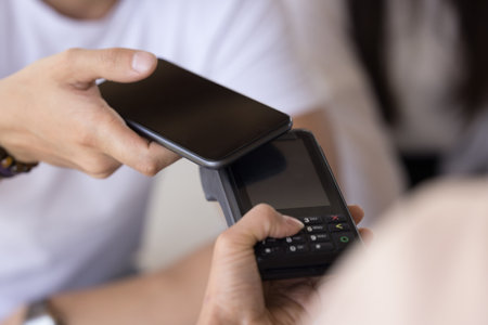 Male hand holding smartphone, applying camera to payment terminal blank screen, paying bill, purchase, service, using bank financial application for contactless connectionの写真素材