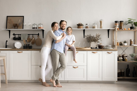 Happy young family with little kid looking at camera posing in modern renovated kitchen, feel satisfied after repair works enjoy fashionable furniture. Services, bank loan, new house owners portraitの写真素材