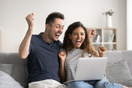 Couple read e-mail celebrate great unbelievable commercial offer with fists clenched scream with joy relish success, achievement or advancement. Jackpot, auction winners family enjoy moment of victoryの写真素材